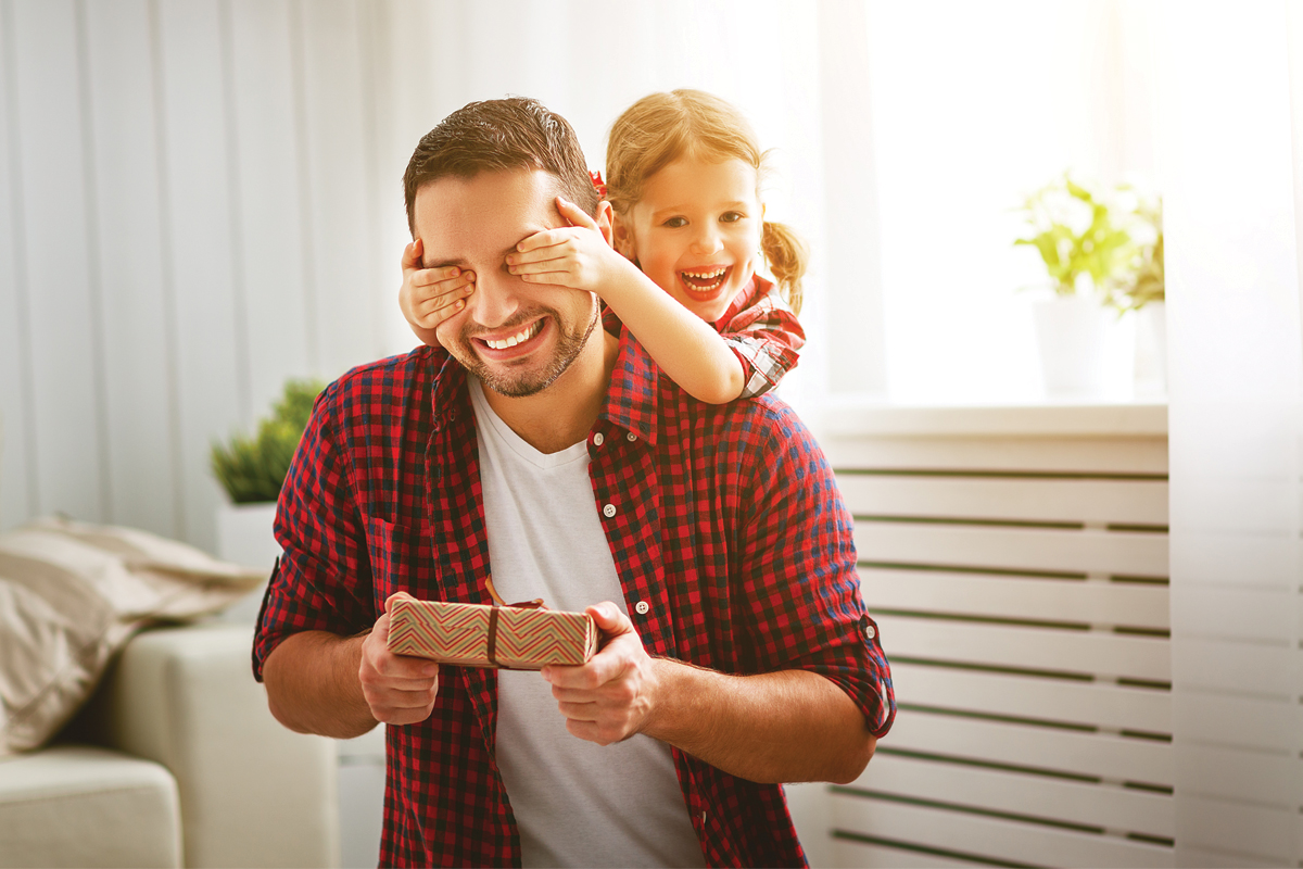 Daughter covering her fathers eyes from behind with her hands